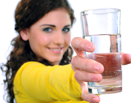 A homeowner shows off a glass of pure, clean water after using an Austin water softener.