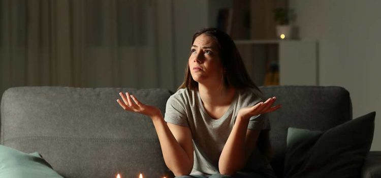 Woman sitting in dark living room with candles during a power outage