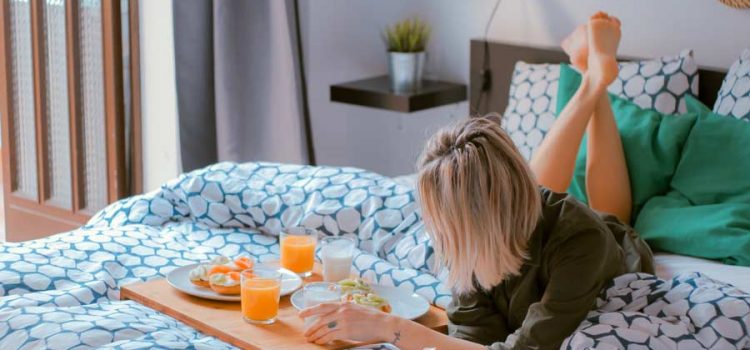 Guest lying on a hotel bed with a breakfast tray