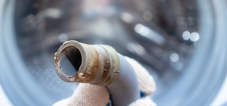 Close up of a wasing machine connector covered in limescale buildup.