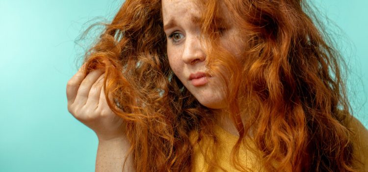 A woman staring sadly at a handful of her hair damaged by hard water.