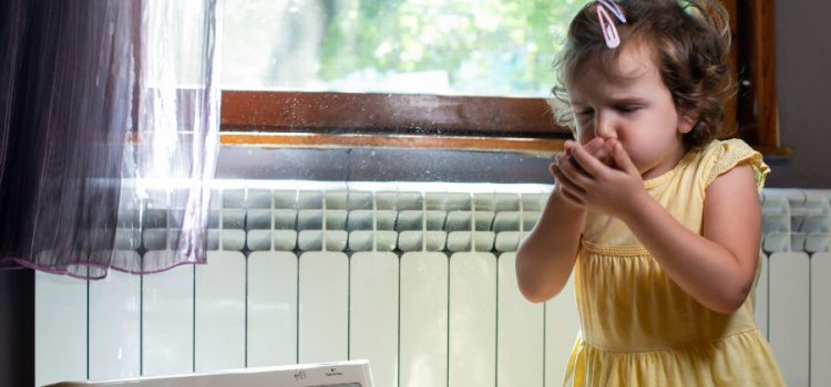 A little girl coughing and sneezing in her home due to poor indoor air quality.