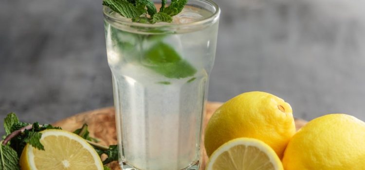 glass of cold water flavored with mint and surrounded by fresh cut lemons, water purified by trustworthy company specializing in Water Treatment in Austin, Tx