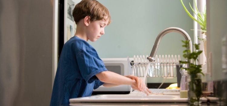 little boy washing his hands in kitchen sink