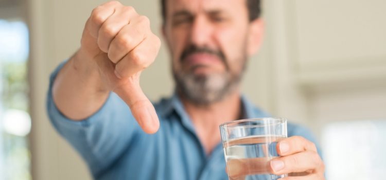 A man giving a thumbs down to his low quality water due to his lack of water filtration in Austin TX