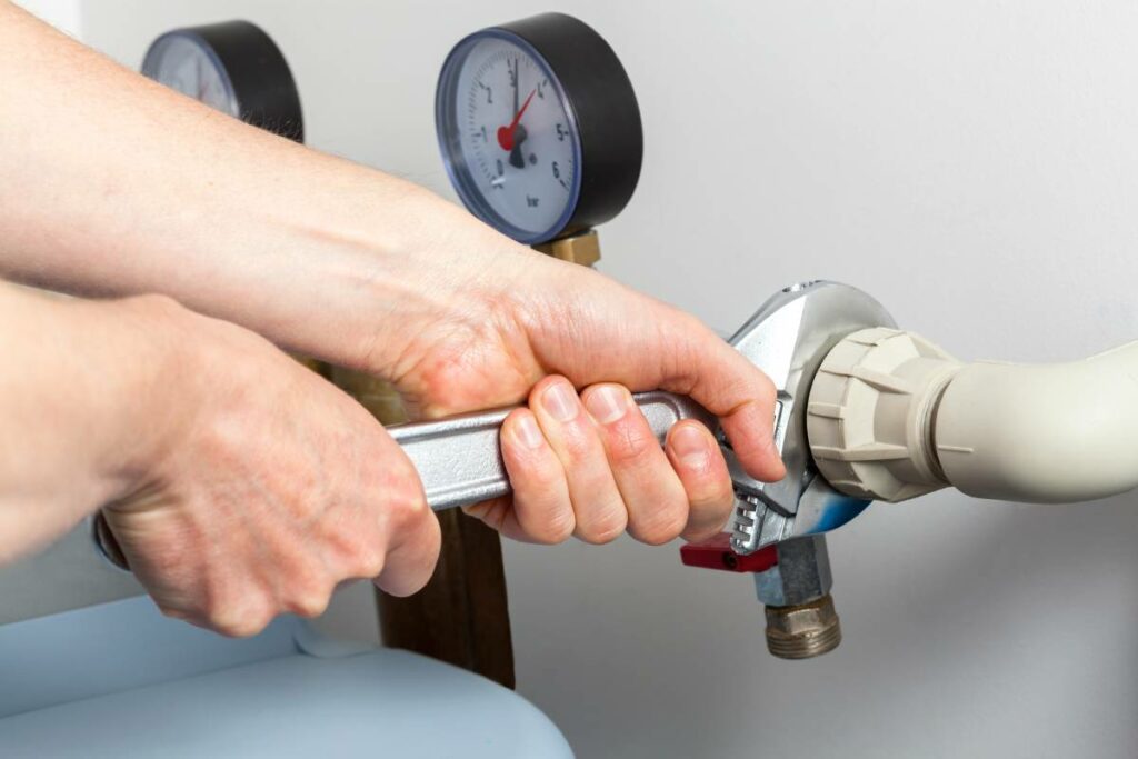 Close-up of hands using a wrench to adjust connectors on a water softener