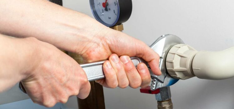 Expert technician in Austin TX adjusting connectors on water softeners with a wrench.