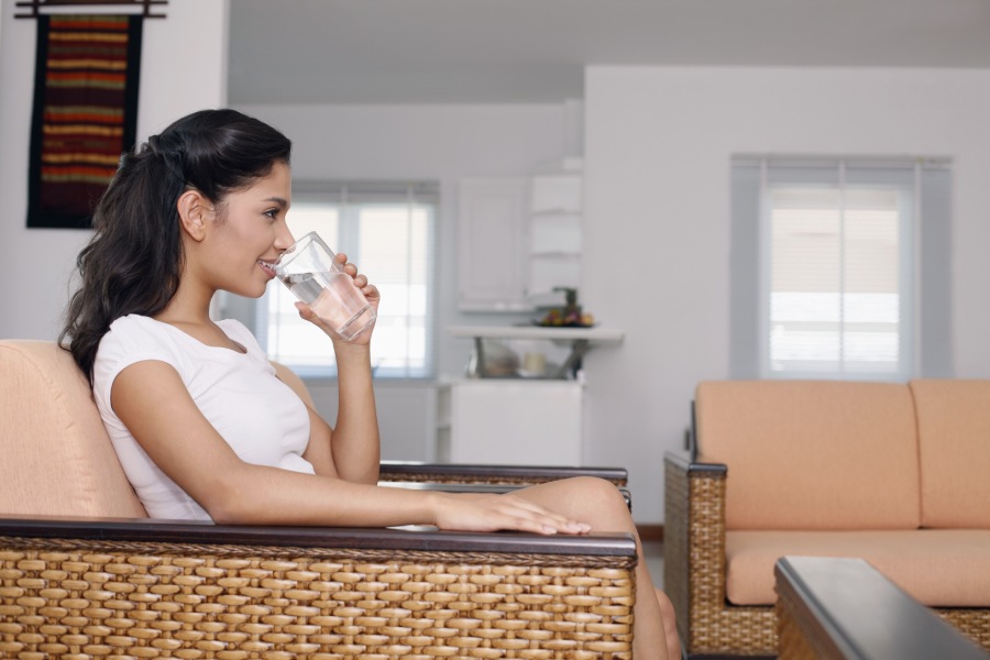 Woman sitting in a rattan chair and drinking a glass of nice reverse osmosis water