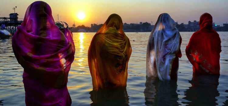 Group of people dressed in spiritual robes performing a ritual standing in a river